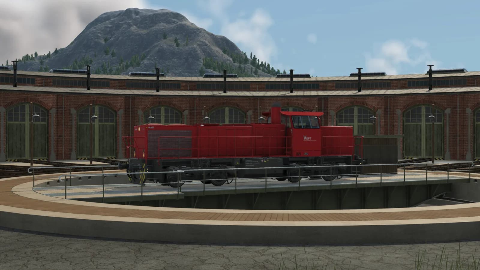 Red locomotive beside roundhouse turntable